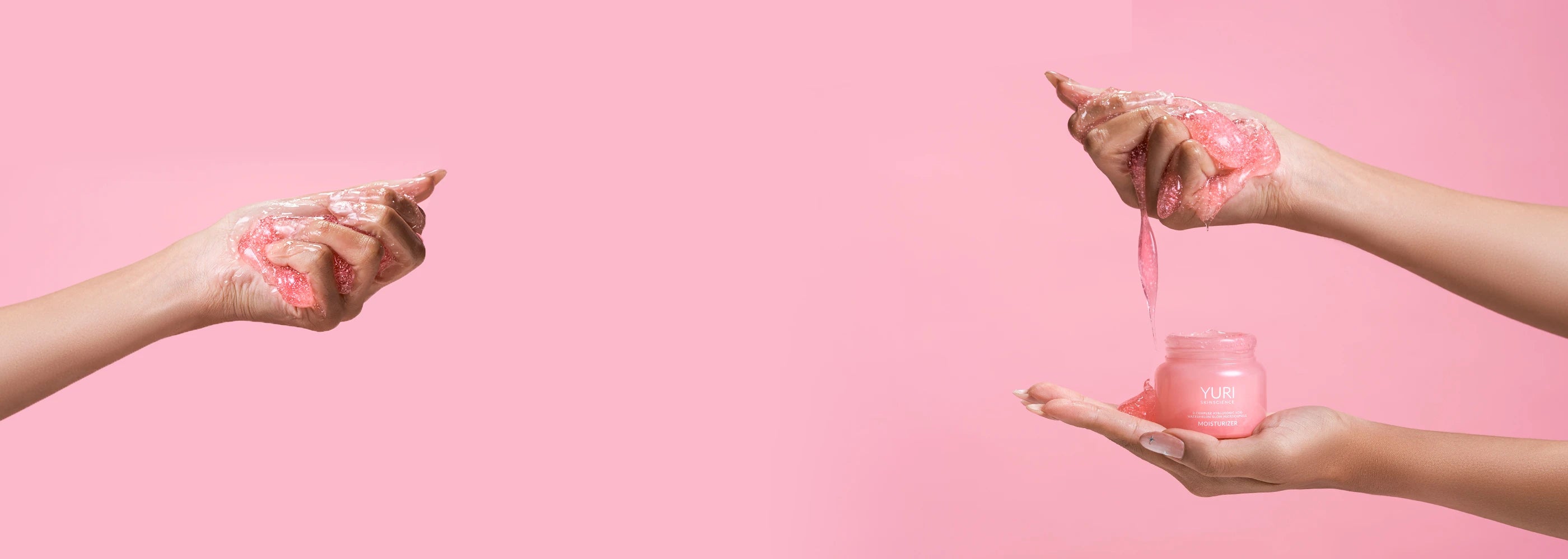 Hands holding Yuri Skinscience moisturizer against a pink background